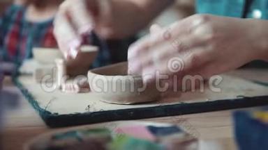 创造了一盘粘土。 在陶艺课上，一个双手漂亮的女孩雕刻着一份奇怪的工作